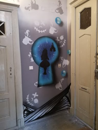 Schlüsselloch für Alice im Wunderland Eine Innenwand mit einer silhouettierten Alice-Figur in einem blauen Schlüsselloch und verspielten Elementen rundherum.
