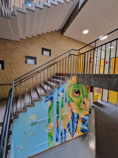 Treppenhausgestaltung – Ein Papagei im Flug Innenaufnahme eines Treppenhauses mit einem großen Graffiti-Wandbild eines Papageienkopfes mit bunten Federn und Seifenblasen.