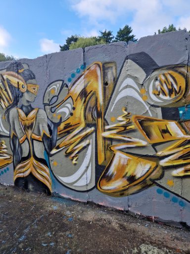 Die goldene Else Kunstvolles Graffiti an einer Außenmauer in glänzenden Gold-, Gelb- und Schwarztönen.
