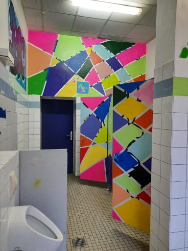 Toilettenraum neu durchgestylt Ein Gang mit mehreren Toilettentüren, die alle mit leuchtenden geometrischen Farbmustern bemalt sind.