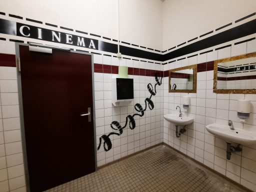 Cinematisches Schulprojekt - Toilettengestaltung Modernes Toilettenvorraum mit zwei weißen Waschbecken und Wandgestaltung die an das Thema Filmrollen erinnert.